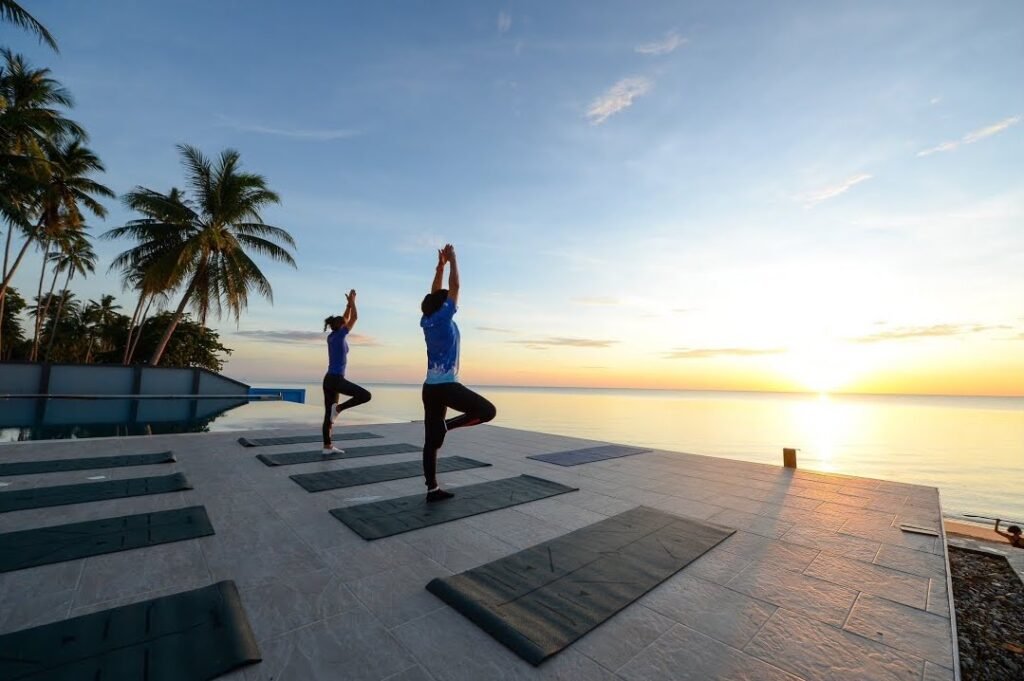 Women doing yoga standing pose by the sea